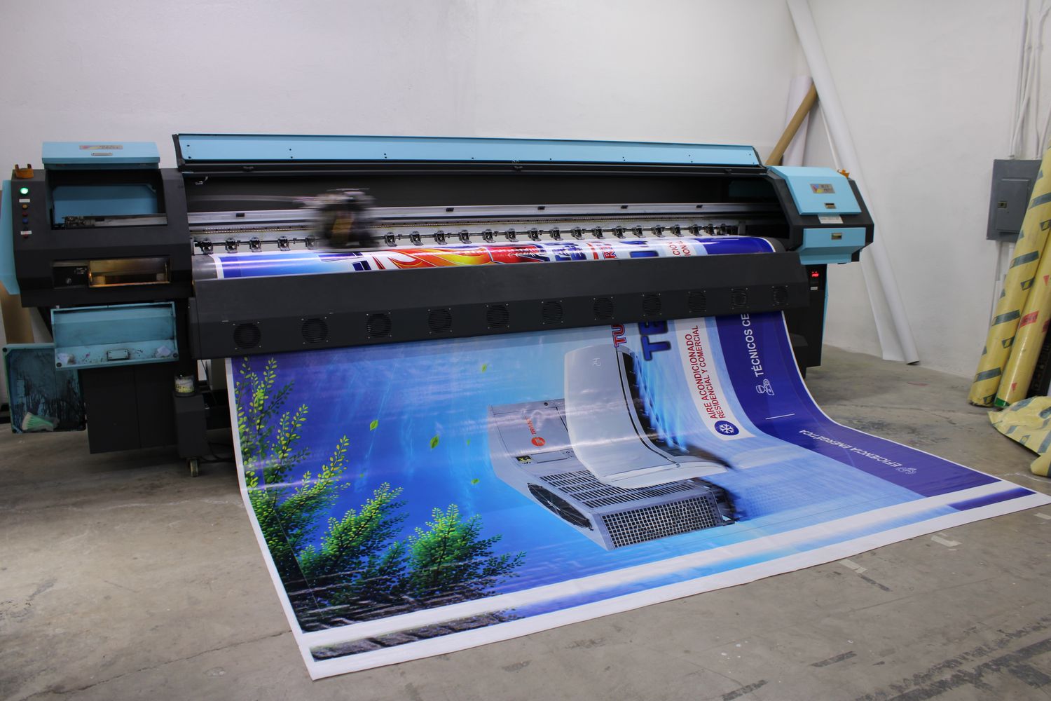 Impresora de gran formato imprimiendo una lona en el taller
